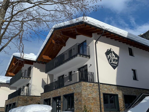 A hotel with a stone facade, balconies, and a sign reading "Alpen Chalet."