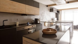 A modern kitchen with a central island, wooden cabinets, and a large window providing natural light. - Apartment With Sauna (Schladming)