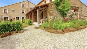 A stone building with a covered porch and a gravel driveway. - Cozy Cottage in Roussines, Dordogne (Roussines)