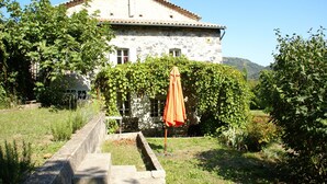 A stone building with a tiled roof, surrounded by greenery and a clear sky. - Holiday Home in Ardeche Near Chateau Ventadour (Lalevade-d'Ardeche)