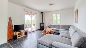 Una sala de estar moderna con un sofá seccional, un televisor de pantalla plana, un mueble de madera y un estufa a leña.