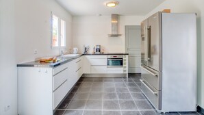 Una cocina moderna con armarios blancos, un refrigerador de acero inoxidable y un horno empotrado.