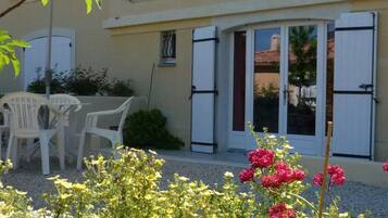 A building with a patio area, white shutters, and a door with glass panels.
