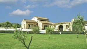 A stone building with a tiled roof, a grassy lawn, and a clear sky. - Vineyard Villa in Montfrin (Montfrin)