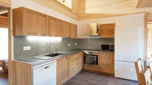 Eine moderne Küche mit Holzausstattung, Geschirrspüler, Backofen, Mikrowelle und Kühlschrank.