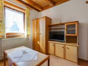 Huoneessa on puinen kaappi, televisio ja pöytä, jonka päällä on lasi.