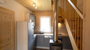 A compact kitchen with grey cabinets, a white refrigerator, and a wood-burning stove. - Amazing House With Balcony (Sankt Georgen am Kreischberg)