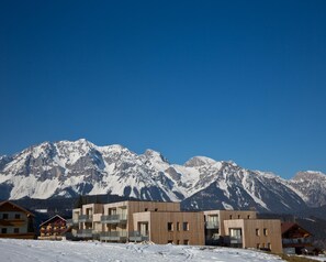 A modern building with multiple balconies and a mountain backdrop.