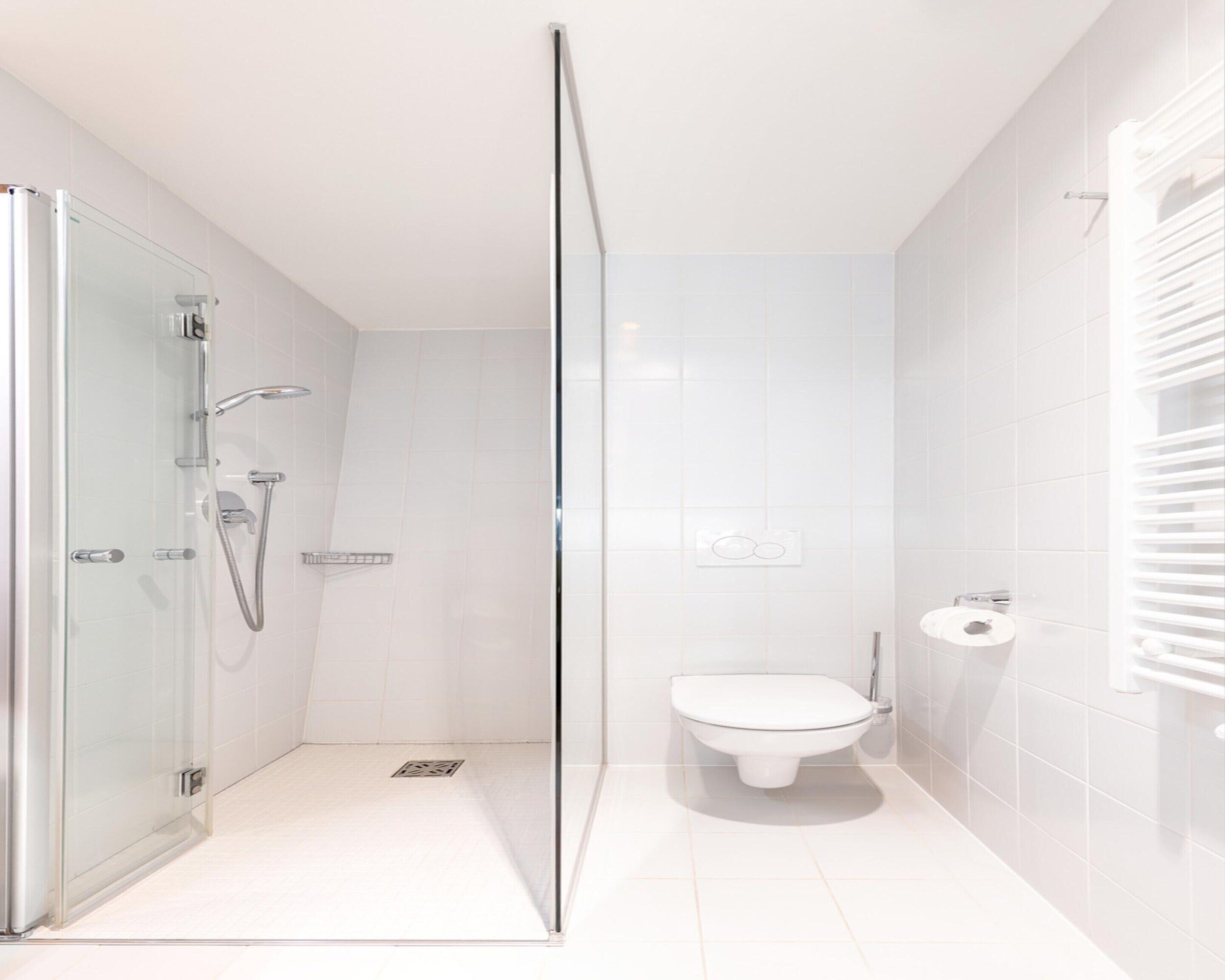 Et moderne badeværelse med et glasvægshus, toilet og håndvask.