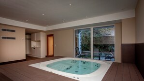 A modern bathroom with a large bathtub, a shower area, and a glass door leading to a garden. - Posh Mansion in Sankt with 2 Saunas, Whirlpool, Hot Tub (Sankt Anton am Arlberg)