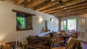 A cozy room with a wooden ceiling, a zebra-patterned sofa, a dining area with wicker chairs, and a stone wall. - Cottage Bliss in Roussines (Roussines)