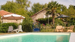 A swimming pool with lounge chairs, a stone building, and a palm tree. - Cottage Bliss in Roussines (Roussines)