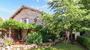 A stone house with a wooden porch, a stone wall, and a ladder leaning against the house. - Cottage Bliss in Roussines (Roussines)