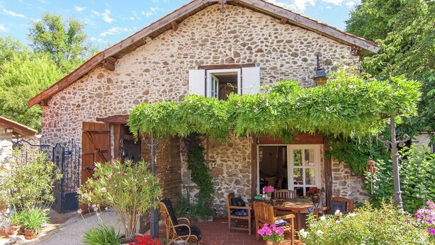 A stone house with a garden, outdoor seating, and a wooden door. - Cottage Bliss in Roussines (Roussines)