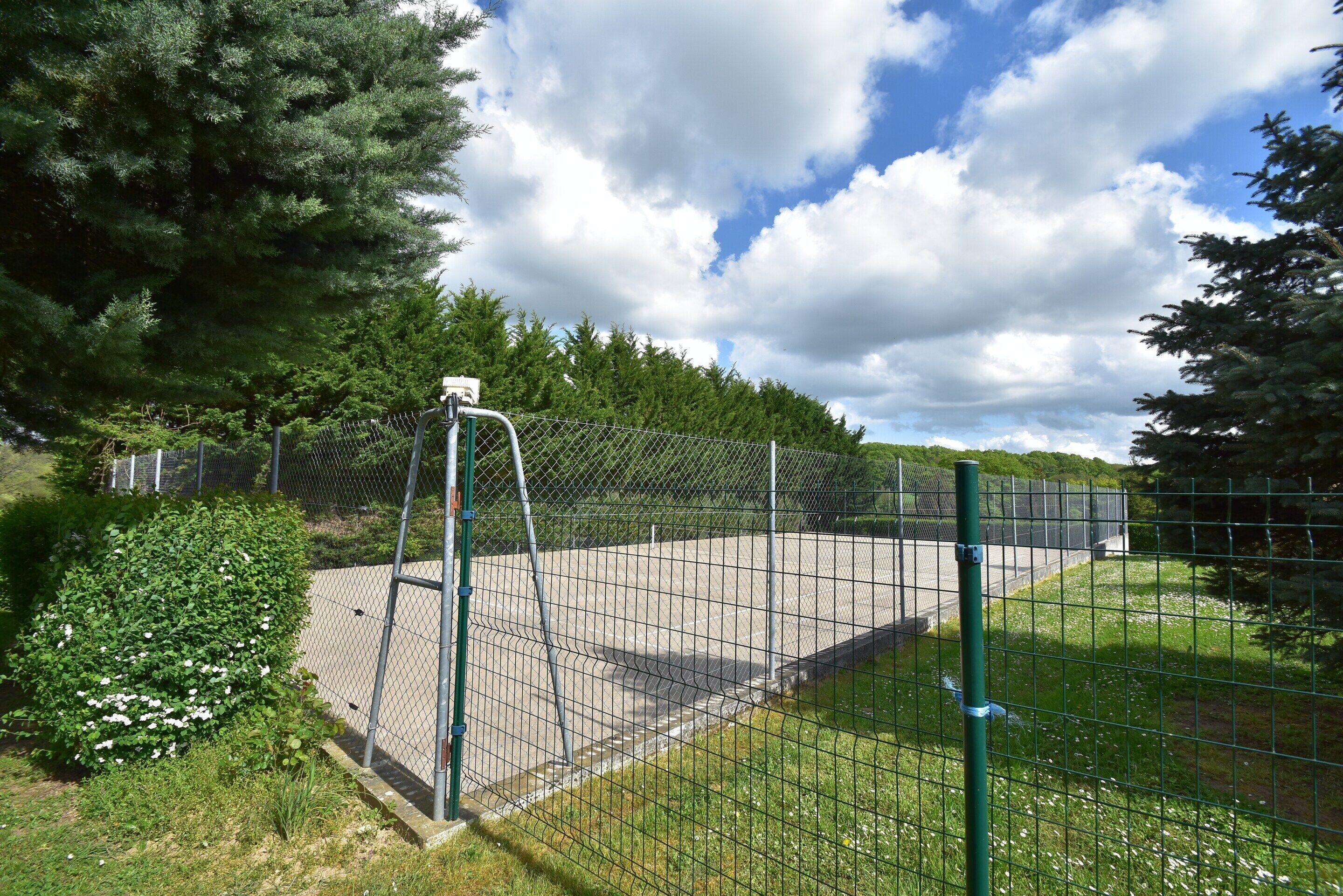 Un espace clos, agrémenté d’un sentier, de verdure et d’un ciel dégagé.