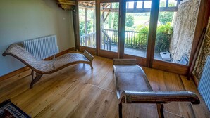 A room with wooden flooring, two wicker lounge chairs, a radiator, and large windows with a view of greenery outside. - Beautiful Farmhouse With Private Pool (Perchede)