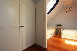A bedroom with a wooden floor, a bed, a small bedside table with a plant, and a ceiling light fixture. - Dike House in Schoondijke Near Beaches (Schoondijke)