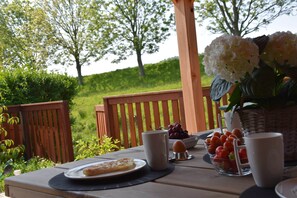 A table set outdoors with a plate of food, a bowl of grapes, and a vase of flowers. - Dike House in Schoondijke Near Beaches (Schoondijke)