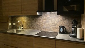 A modern kitchen with wooden cabinets, a stainless steel sink, a microwave, and a coffee maker. - Dike House in Schoondijke Near Beaches (Schoondijke)