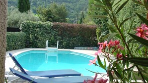 A swimming pool with lounge chairs and a yellow umbrella, surrounded by greenery and hills. - Sunny Villa Stay in Nyons (Nyons)