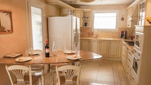A kitchen with a dining table, chairs, a refrigerator, and a window. - Chic Narbonne Pool Retreat (Narbonne)