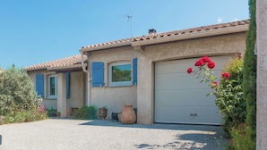 A two-story house with a tiled roof, a garage, and a garden with potted plants and flowers. - Chic Narbonne Pool Retreat (Narbonne)