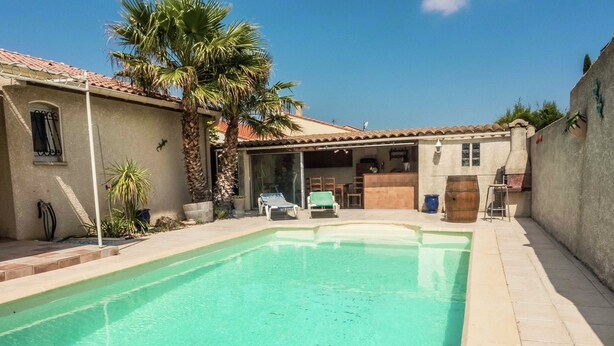 A swimming pool with a tiled deck, a covered patio area, and a building with a tiled roof. - Chic Narbonne Pool Retreat (Narbonne)