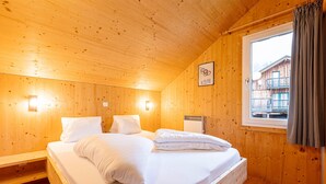 A wooden cabin bedroom with a bed, two bedside tables, a window with curtains, and a wall-mounted picture. - Nice Chalet With Terrace (Hohentauern)
