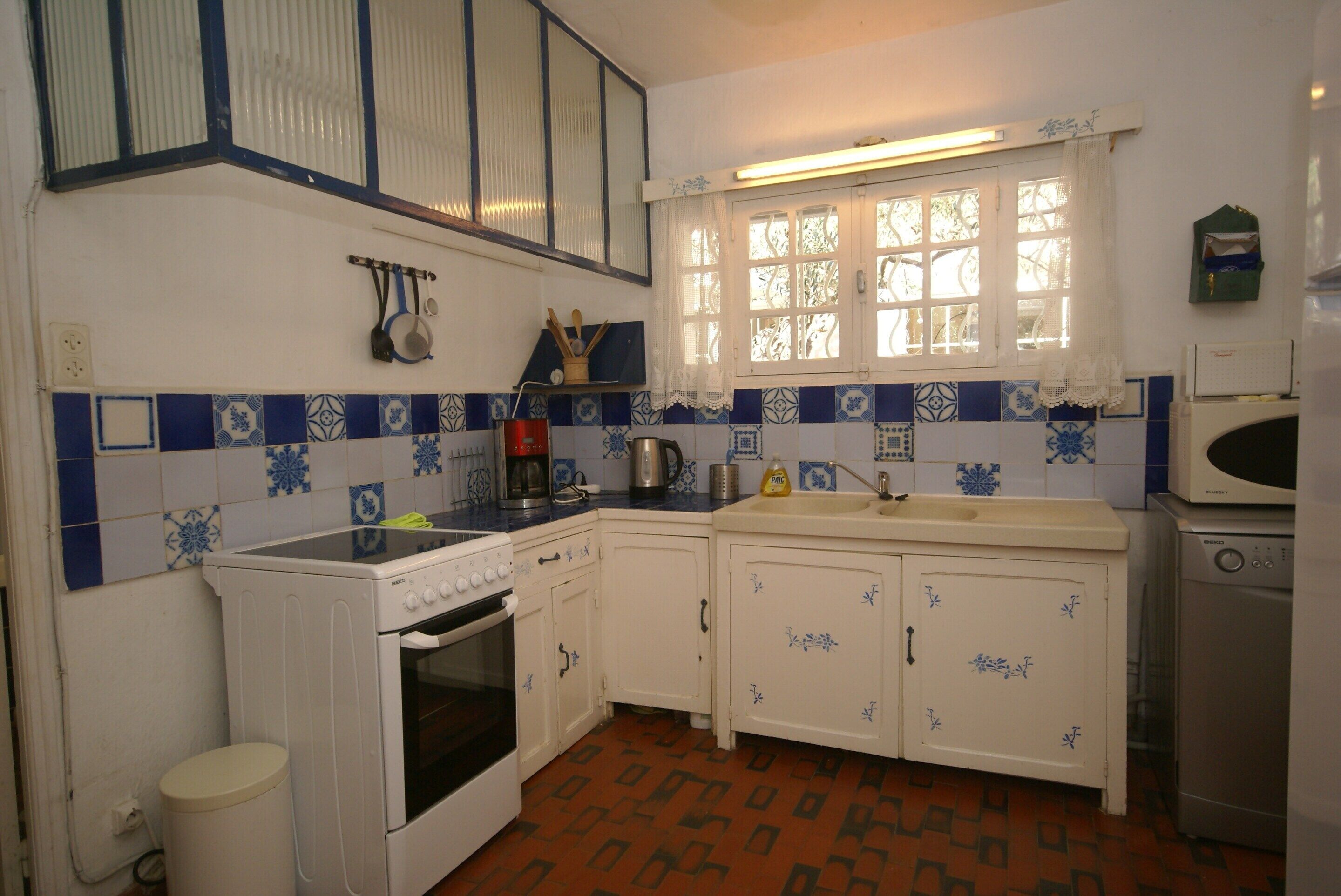 Una cocina con armarios blancos, estufa, fregadero y microondas.