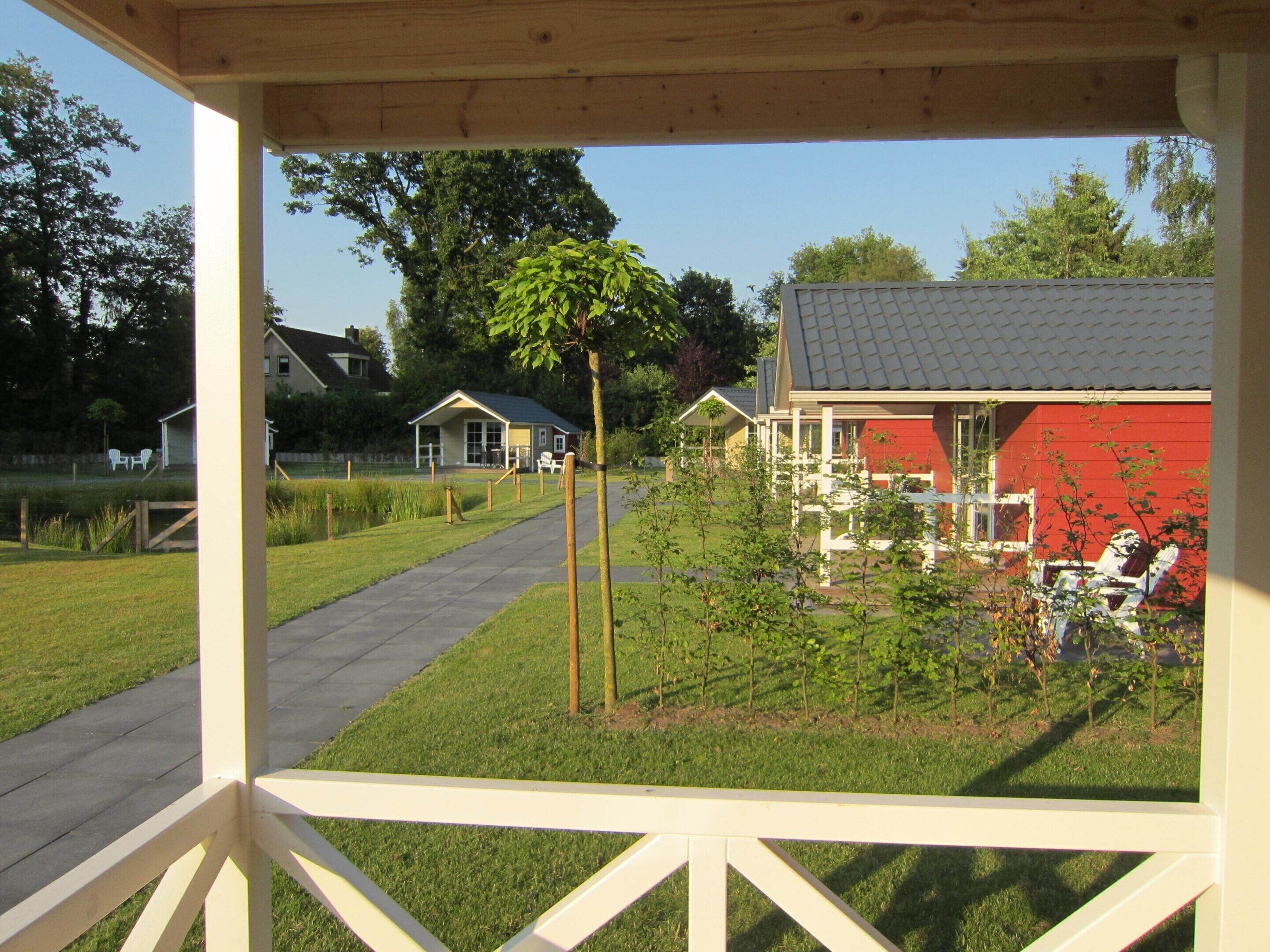A covered outdoor area with a pathway leading to a red building and a smaller structure in the background.