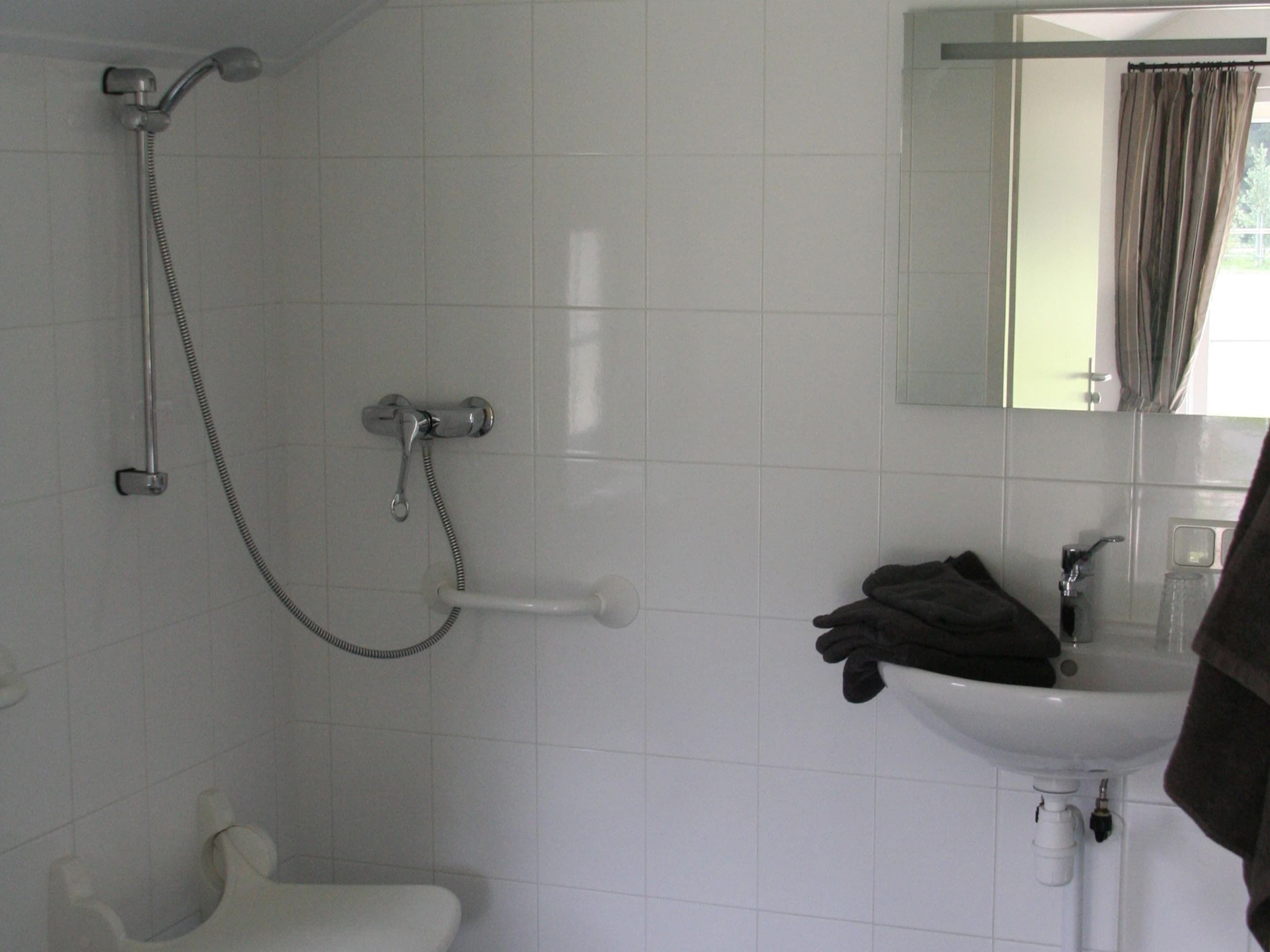 A bathroom with a shower, toilet, sink, and a mirror with a curtain.