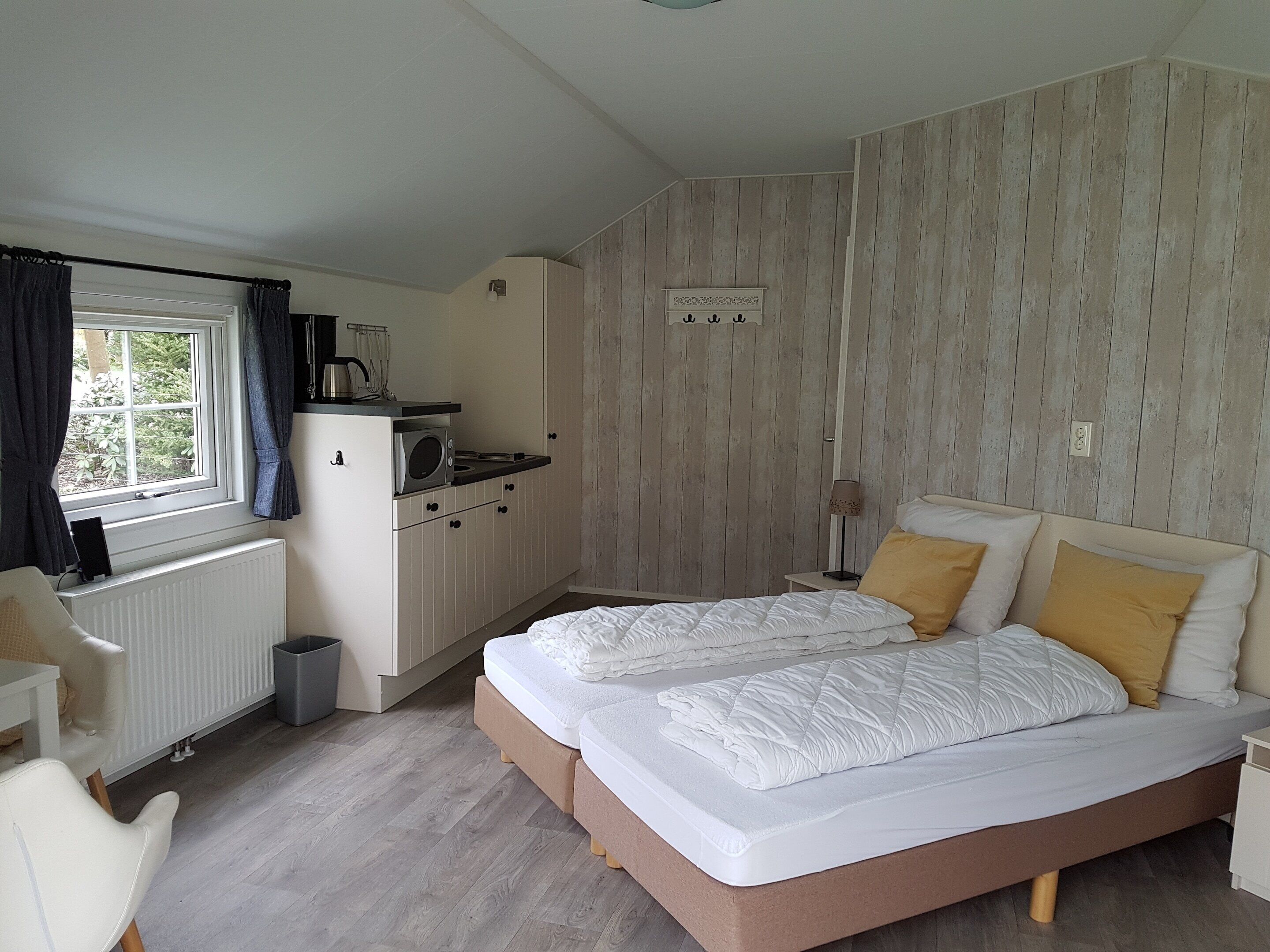 Een kleine slaapkamer met een bed, nachtkastje en een klein keukenblok.