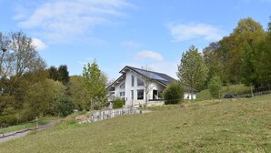 A modern house with a sloped roof, a small attached garage, and a fenced yard. - Peaceful Getaway in Nature (Varsberg)