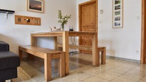 A room with a wooden table, benches, a black sofa, and a wooden door. - Peaceful Getaway in Nature (Varsberg)