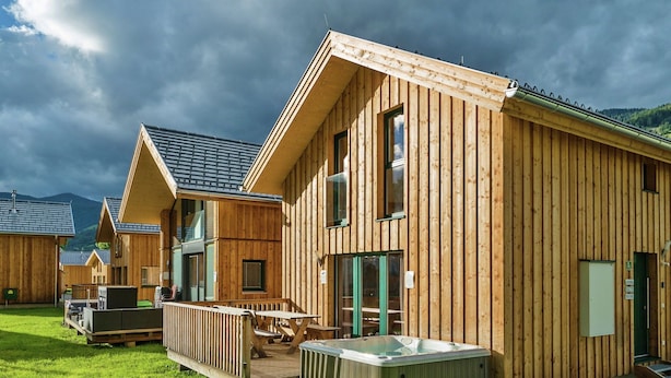 Een rij houten blokhutten met een hottub en terras.