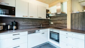 Een moderne keuken met witte kasten, een inbouwoven en een koffiezetapparaat.