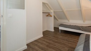 A bedroom with a sloped ceiling, a bed, a wooden hanger, and a closet. - Elegant Apartment in Hoorn With Roof Terrace (Hoorn)