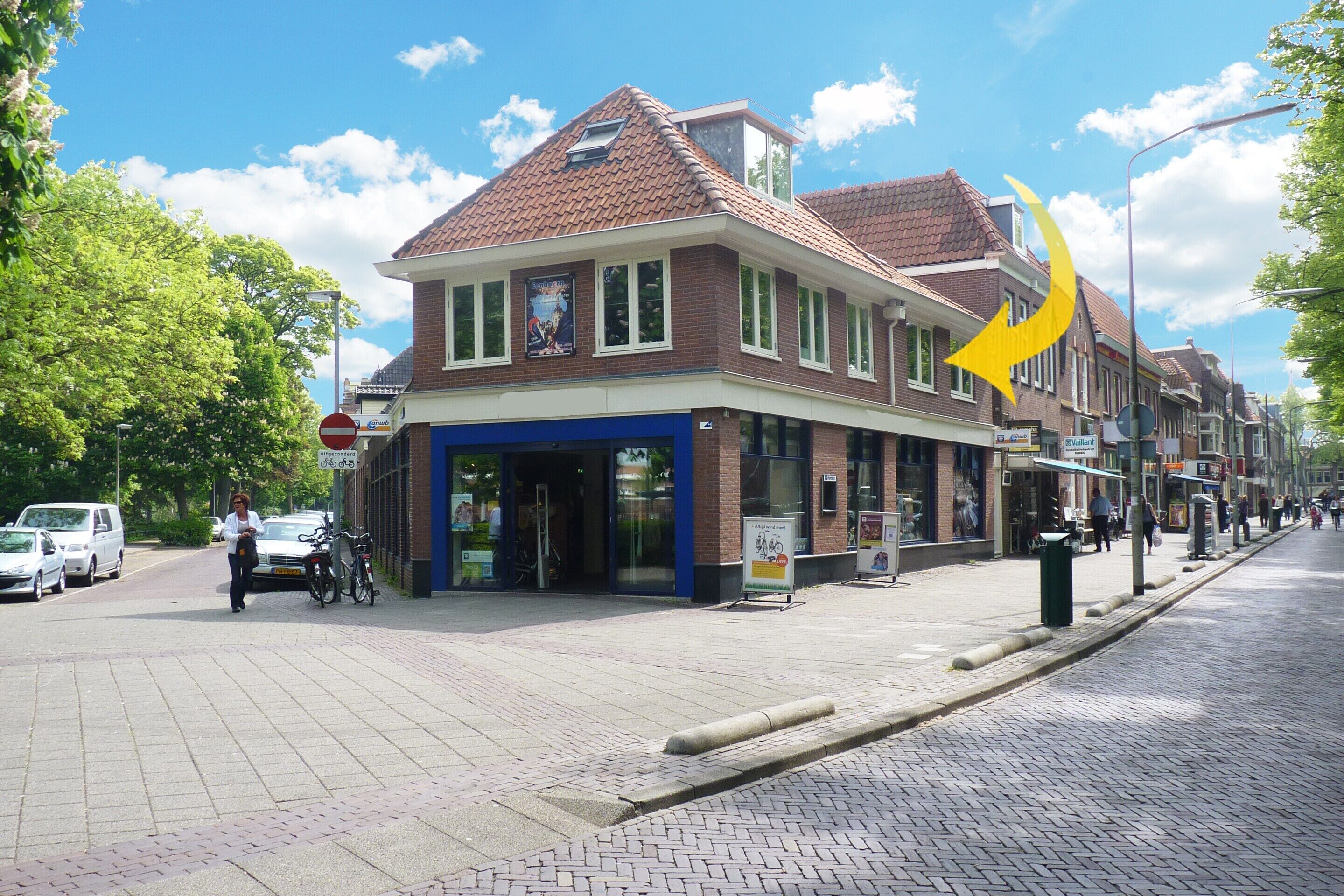 A building with a brick facade, large windows, and a blue awning.