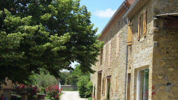 A stone building with a gravel driveway, large trees, and potted plants. - Villa in Conilhac With Private Terrace (Roquetaillade-et-Conilhac)