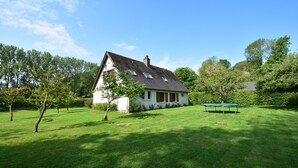 A house with a sloped roof, a small porch, and a well-maintained lawn. - Bungalow in France Near Castle & Hiking Trails (Saint-Pierre-le-Vieux)