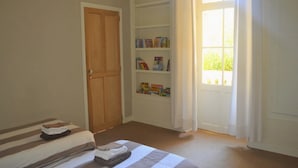 Un dormitorio con una cama, una puerta de madera, una estantería y una ventana con cortinas.