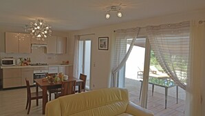 Una cuina moderna amb zona de menjador, un sofà groc, i un patí amb taula i cadires.