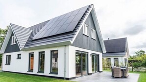 A modern two-story house with a sloped roof, large windows, and a covered patio area. - Holiday Home in Texel Near the Sea (De Koog)