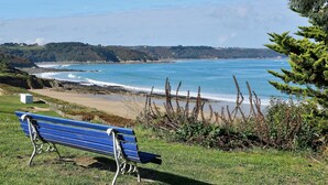 A bench overlooking a coastal landscape with a view of the sea and distant hills. - 17th Century Breton Cottage With Modern Interior on the Edge of a Forest (Huelgoat)