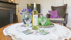 A dining table with a wine bottle, two glasses, and a bowl of greens. - Lovely Cottage near Sea in Wemeldinge (Wemeldinge)