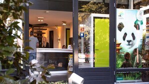 A modern building with a reception desk, a green door, and a panda poster. - Cottage in Rhenen for 6 Person (Rhenen)