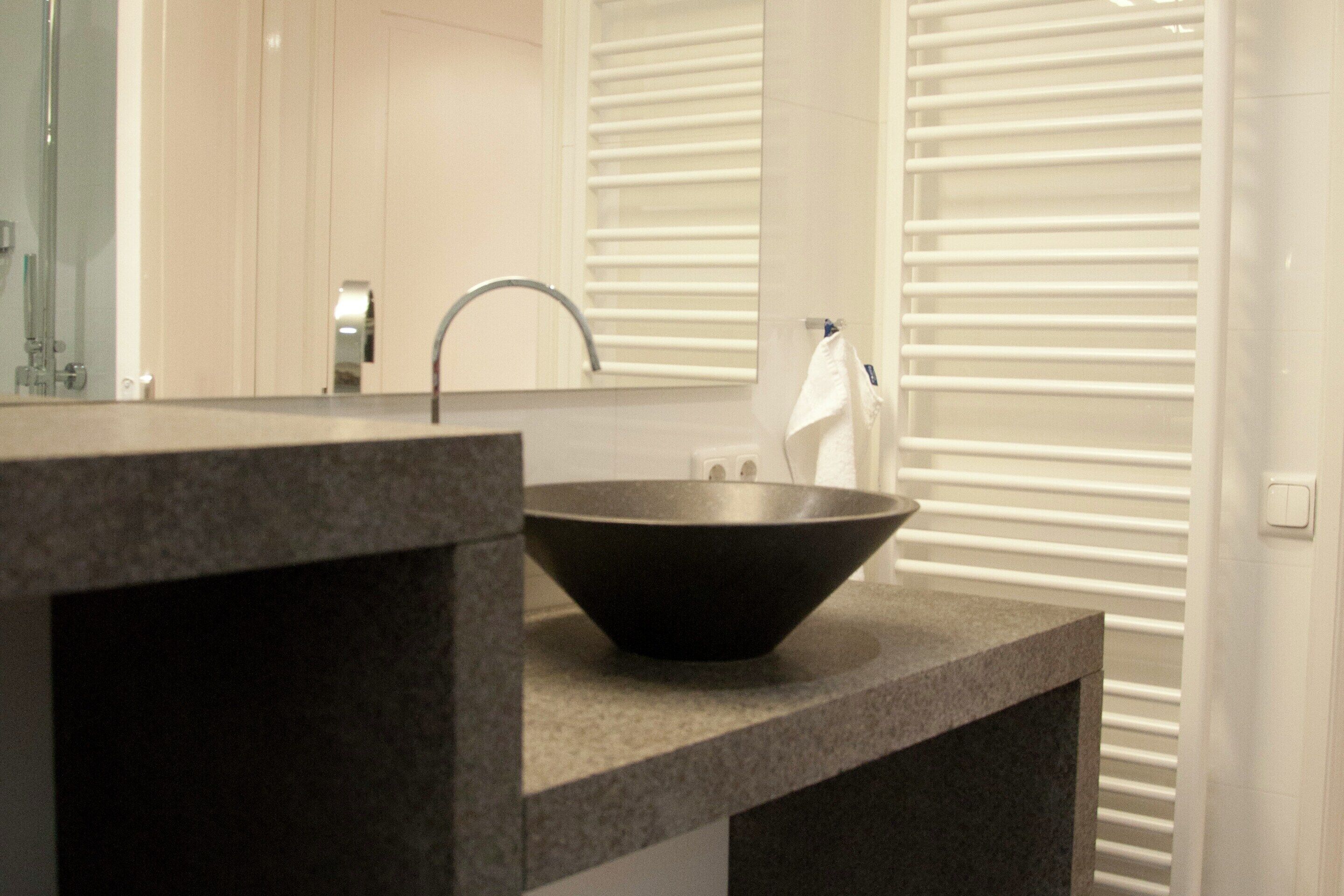 A modern bathroom with a large sink, a mirror, and a towel rack.
