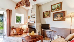 A cozy living room with a fireplace, a television, and a dining area with a table and chairs. - Cottage in Oppede Amidst Vineyards (Oppede)