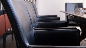 A row of black leather chairs with a metallic frame, a wooden table, and a radiator in the background. - Apartment Near the Belgian Border (Eijsden)