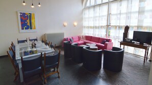 A spacious living area with a dining table, chairs, a red sofa, and a television. - Apartment Near the Belgian Border (Eijsden)